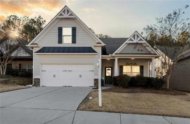 view of front of home featuring a garage, a standing seam roof, stone siding, concrete driveway, and metal roof