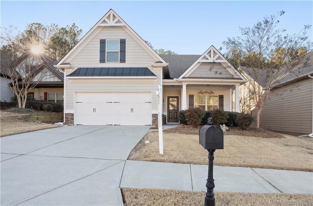 view of front facade with stone siding, driveway, metal roof, and a standing seam roof