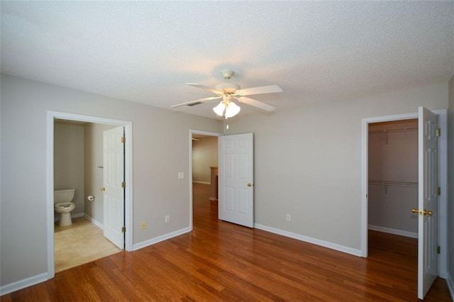 150 Old Mill Rd Unit 115, Cartersville, GA 30120 - unfurnished bedroom featuring wood finished floors, a spacious closet, a closet, connected bathroom, and a textured ceiling