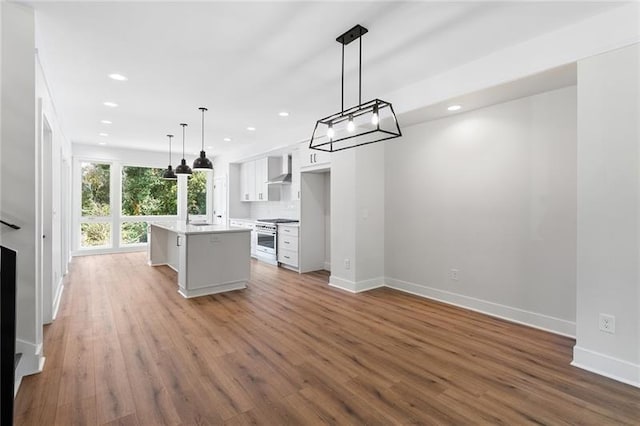 kitchen with white cabinets, wall chimney exhaust hood, a kitchen island, hanging light fixtures, and high end stove