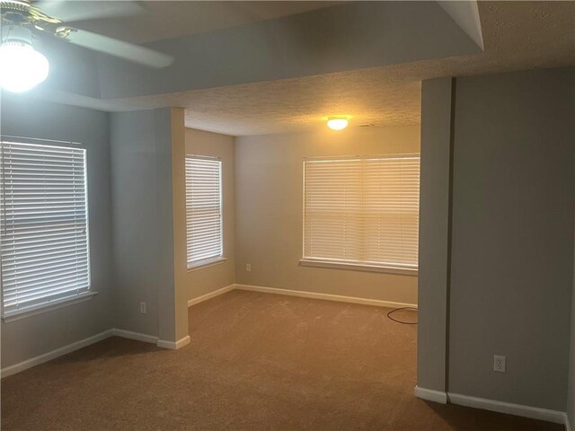 empty room featuring carpet floors, baseboards, ceiling fan, and a textured ceiling