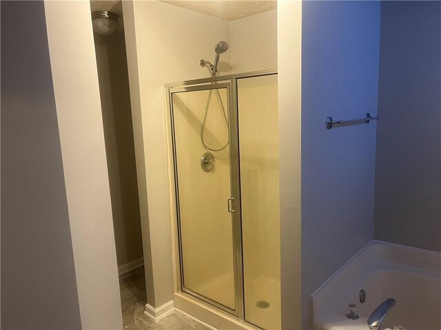 full bath with tile patterned flooring, a stall shower, baseboards, and a bath