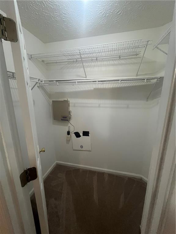 laundry area with baseboards, carpet floors, and a textured ceiling