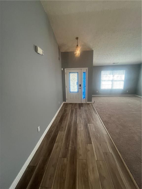 entryway with dark wood finished floors, baseboards, and a textured ceiling