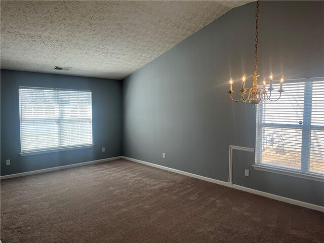 empty room featuring dark colored carpet, vaulted ceiling, a chandelier, a textured ceiling, and visible vents