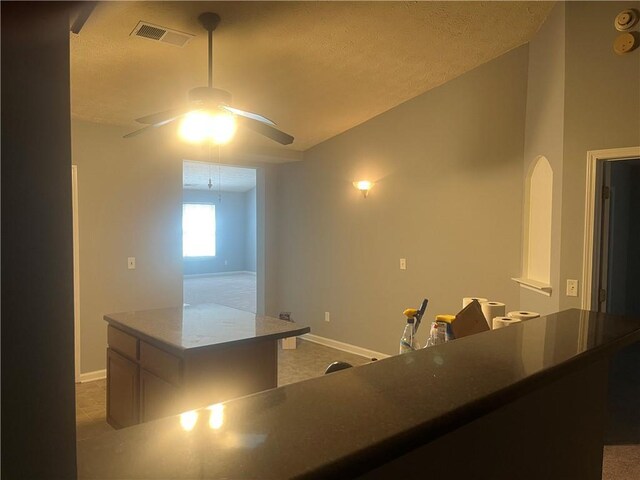 kitchen featuring baseboards, ceiling fan, visible vents, and a center island