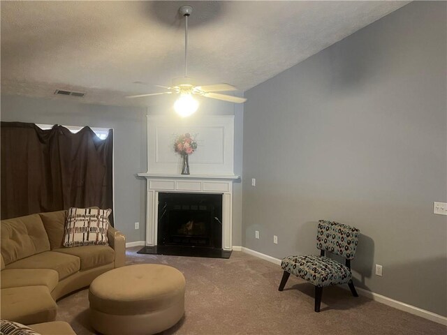 carpeted living room with baseboards, a textured ceiling, ceiling fan, visible vents, and a fireplace