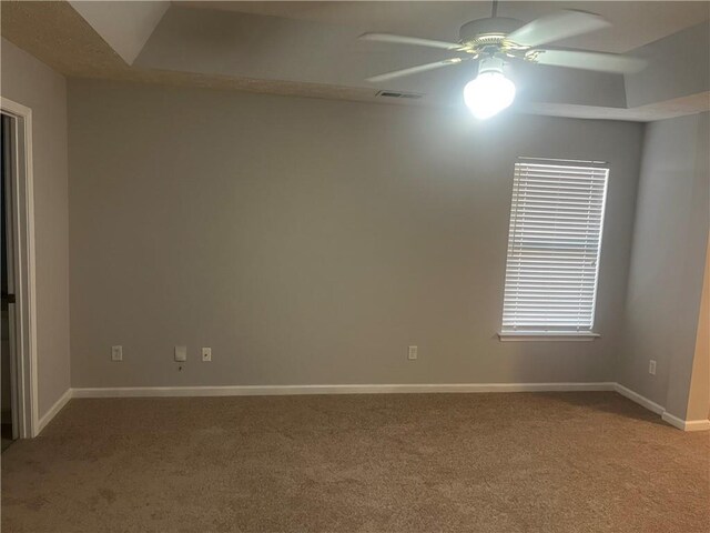 carpeted spare room with visible vents, baseboards, and ceiling fan