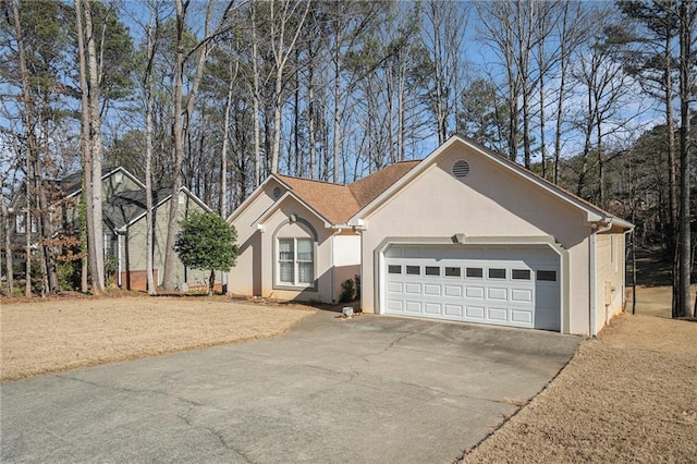 ranch-style home with stucco siding, an attached garage, and driveway