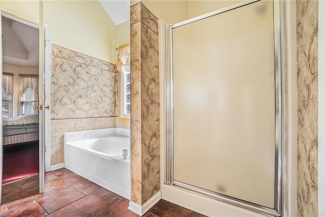 ensuite bathroom with a bath, a shower stall, tile walls, and ensuite bathroom