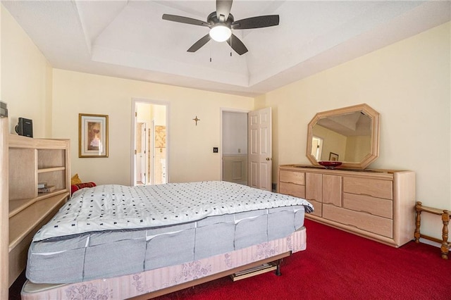 bedroom with a tray ceiling, ceiling fan, and dark carpet