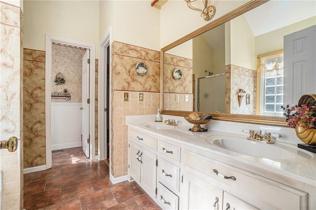 full bathroom featuring double vanity, tile walls, a stall shower, and a sink