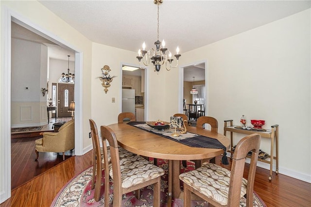 dining area with baseboards, wood finished floors, and a chandelier