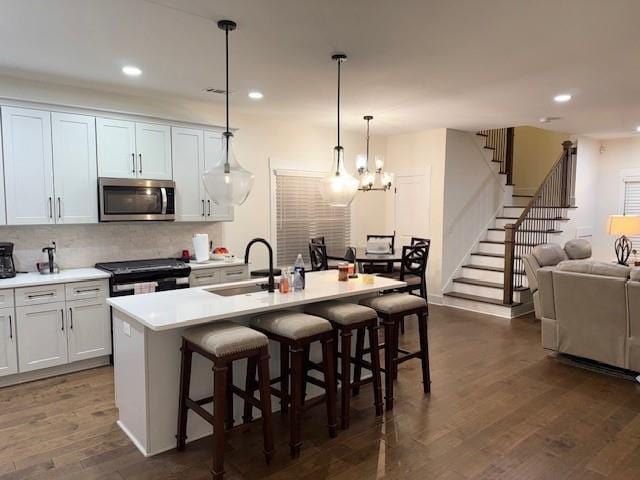 kitchen with white cabinetry, an island with sink, sink, and electric range