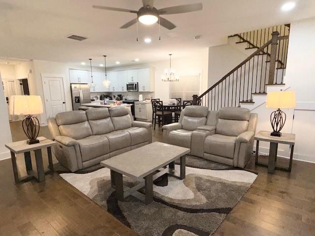 living room with dark hardwood / wood-style flooring and ceiling fan with notable chandelier