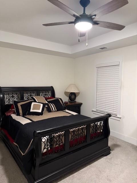 bedroom with ceiling fan, a raised ceiling, and carpet