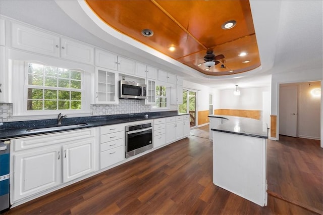 kitchen with appliances with stainless steel finishes, white cabinets, a raised ceiling, and sink