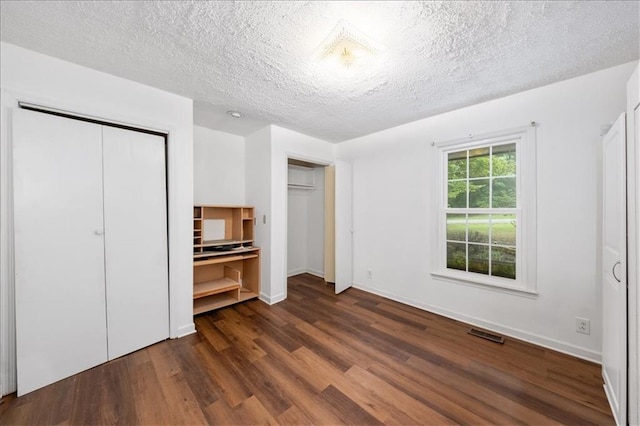 unfurnished bedroom with dark wood-type flooring and a textured ceiling