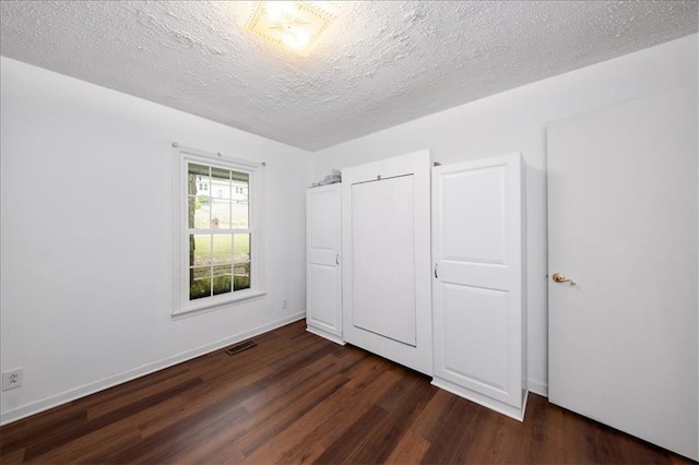 unfurnished bedroom featuring a closet, dark wood-type flooring, and a textured ceiling