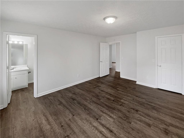 unfurnished bedroom with ensuite bathroom, dark hardwood / wood-style flooring, and a textured ceiling