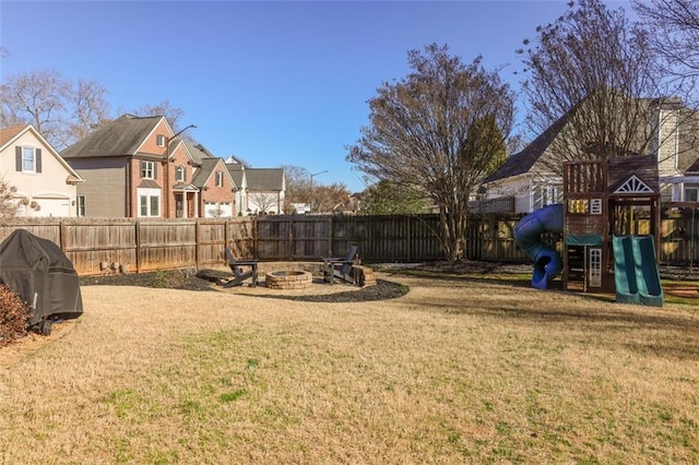 view of yard with fence, a fire pit, and a playground