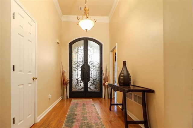 entrance foyer with baseboards, arched walkways, ornamental molding, wood finished floors, and french doors