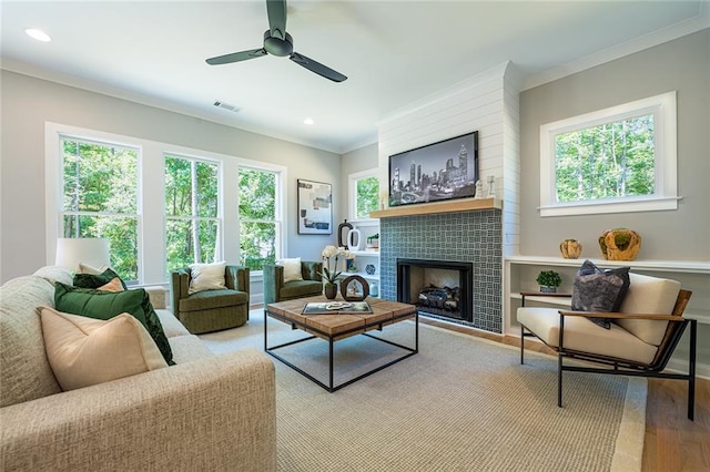 living room with visible vents, light wood-style flooring, ornamental molding, a fireplace, and recessed lighting