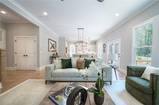 living room with crown molding, baseboards, light wood-style flooring, and recessed lighting