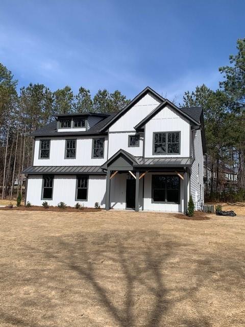 modern inspired farmhouse with metal roof, a standing seam roof, a front yard, and board and batten siding