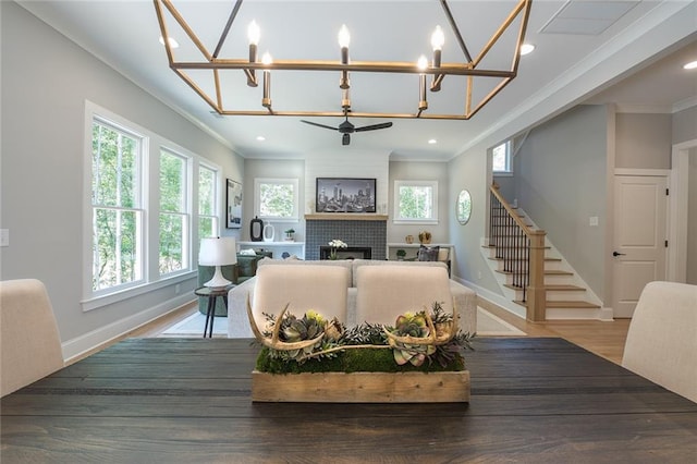 living room with stairs, crown molding, a fireplace, and a healthy amount of sunlight