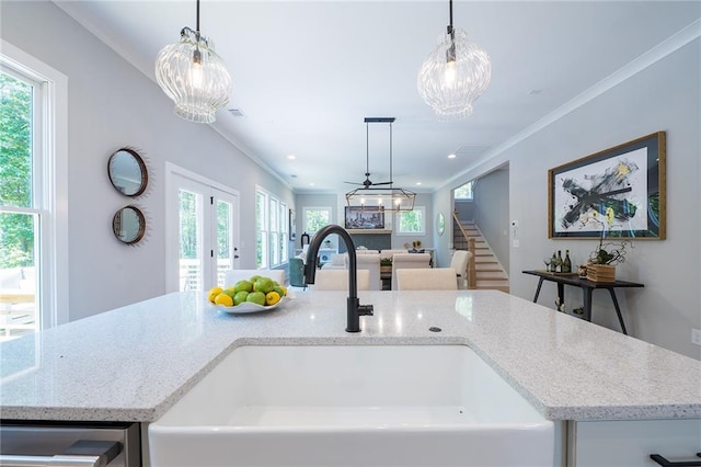 interior details with light stone countertops, a sink, a center island with sink, and decorative light fixtures