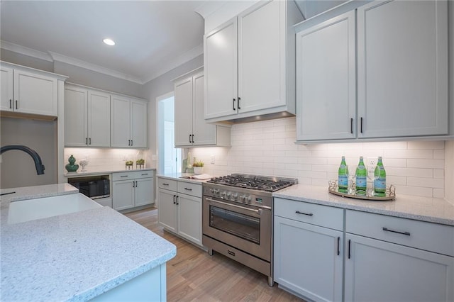 kitchen featuring high end stove, white cabinetry, and a sink