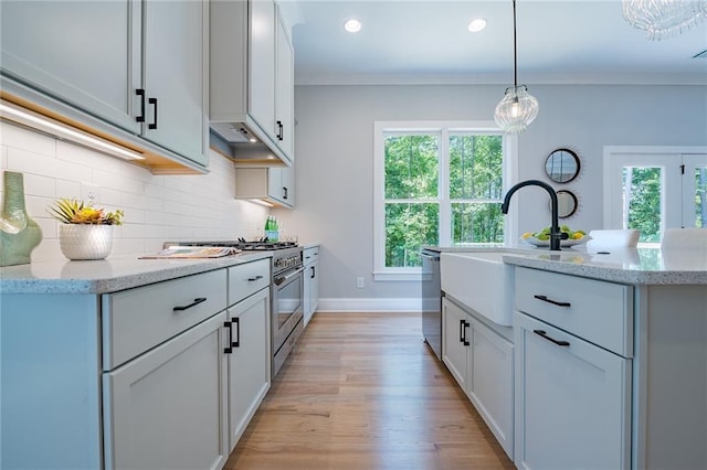 kitchen featuring decorative backsplash, ornamental molding, hanging light fixtures, light stone countertops, and stainless steel appliances