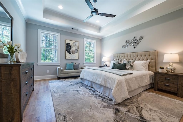 bedroom featuring multiple windows, a raised ceiling, and wood finished floors