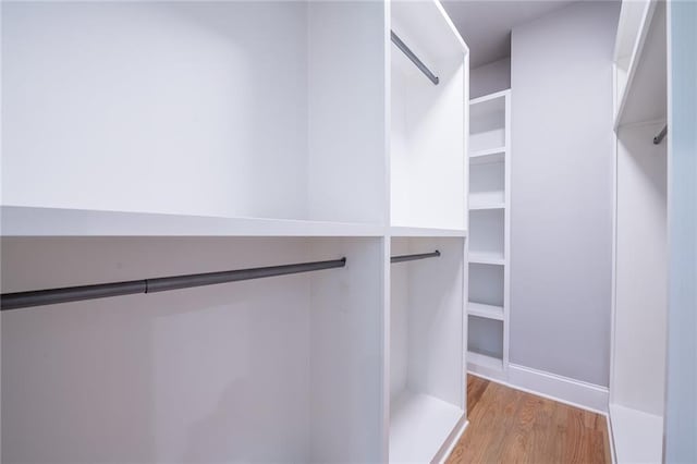 walk in closet with light wood finished floors