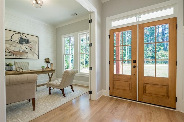 entryway featuring visible vents, baseboards, light wood-style flooring, ornamental molding, and french doors