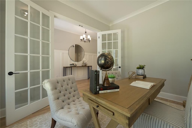 office area with a decorative wall, light wood-style floors, ornamental molding, wainscoting, and an inviting chandelier