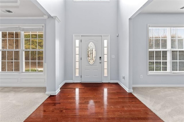 carpeted entrance foyer featuring ornamental molding and a wealth of natural light