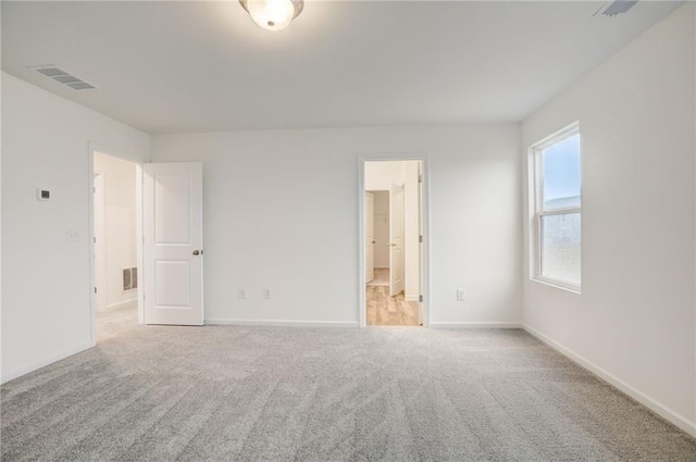 unfurnished bedroom with light carpet and connected bathroom