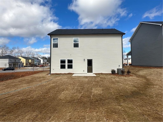 rear view of property featuring a lawn, central AC, and a patio area