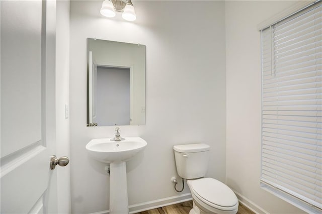 bathroom featuring a notable chandelier, hardwood / wood-style flooring, sink, and toilet