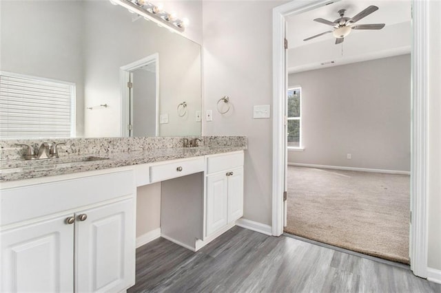 bathroom with double vanity, a sink, ceiling fan, wood finished floors, and baseboards