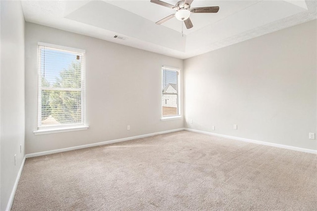 spare room with a wealth of natural light, a tray ceiling, and visible vents