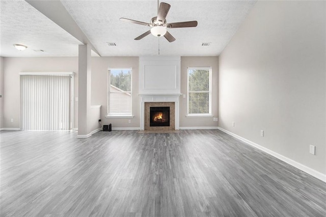 unfurnished living room with a textured ceiling, ceiling fan, wood finished floors, and baseboards