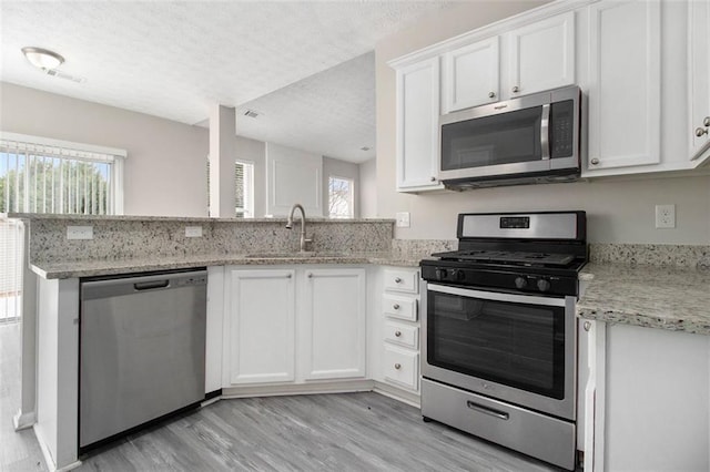 kitchen featuring stainless steel appliances, white cabinets, a sink, and a textured ceiling