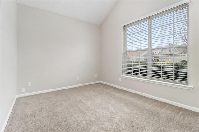 spare room with carpet floors, vaulted ceiling, and baseboards