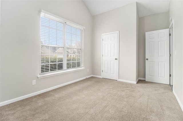 unfurnished bedroom with carpet floors, baseboards, and lofted ceiling