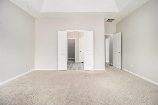 unfurnished bedroom with carpet, a spacious closet, visible vents, and baseboards