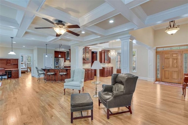 living area featuring a healthy amount of sunlight, light wood-style floors, and ornate columns