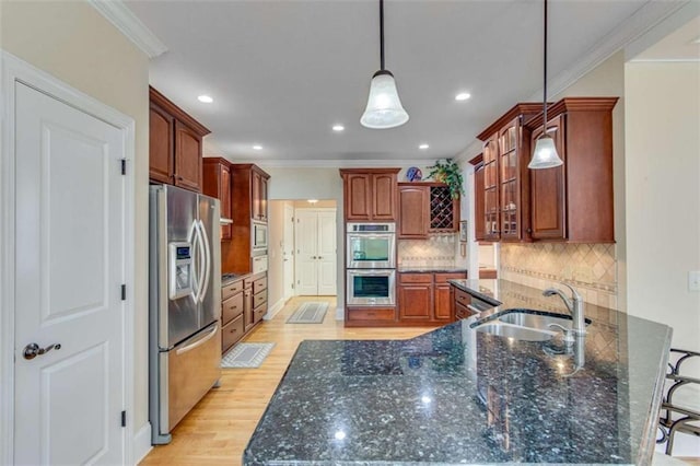 kitchen with light wood-type flooring, a sink, appliances with stainless steel finishes, a peninsula, and crown molding